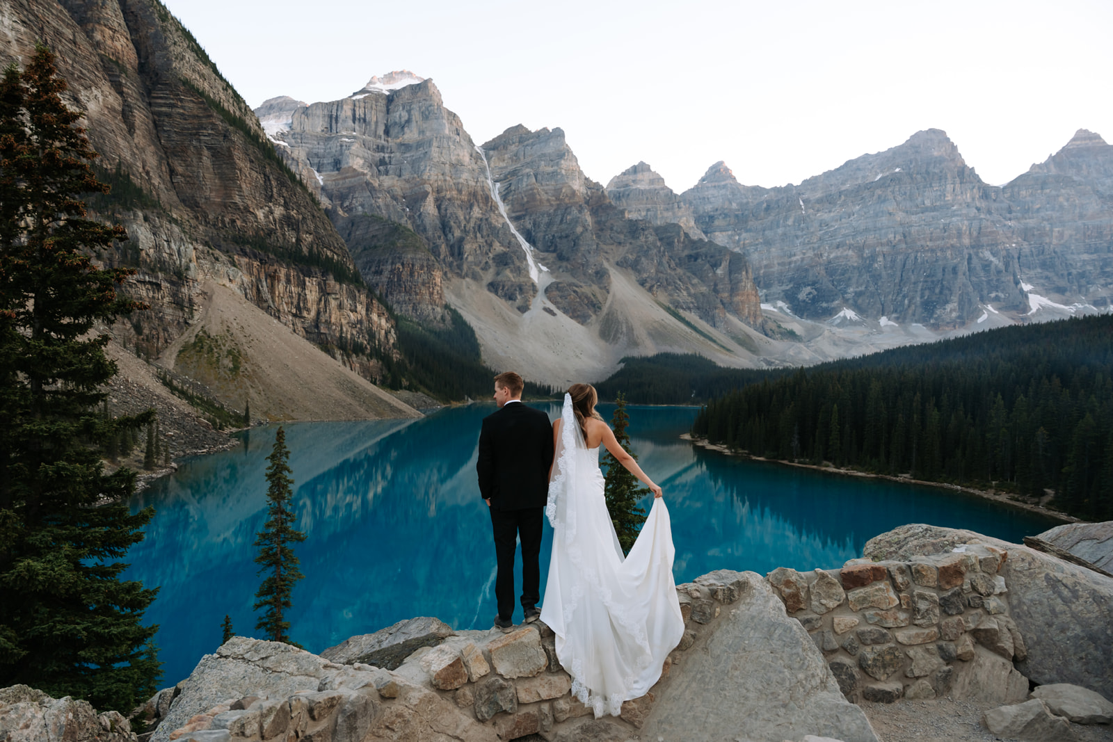 A bride and groom look out over Moraine Lake from the rock pile